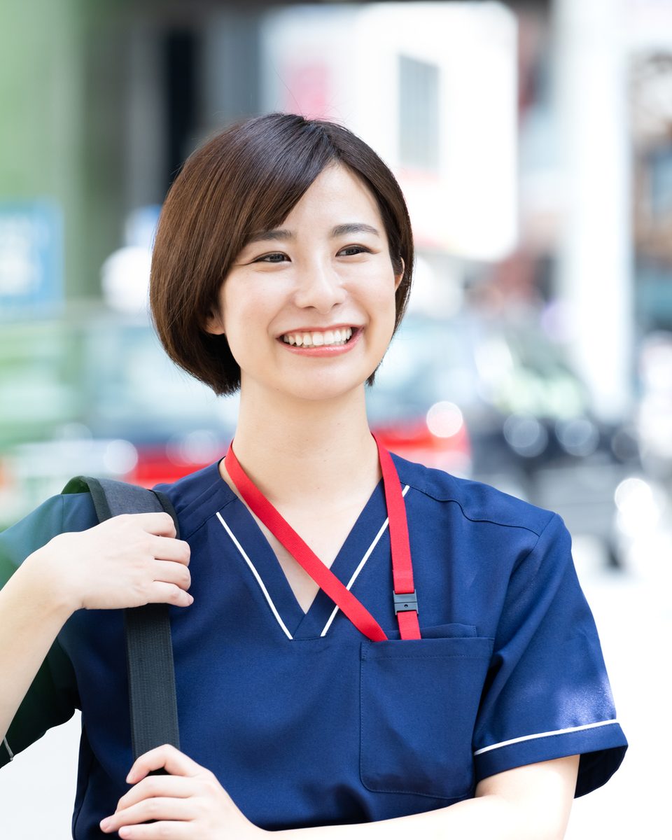訪問バッグを肩にかけ、笑顔で利用者さんのお宅へ向かうヘルパー