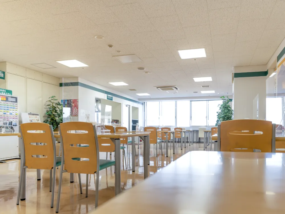 窓の大きな社員食堂。長いテーブルといすが並んでいる